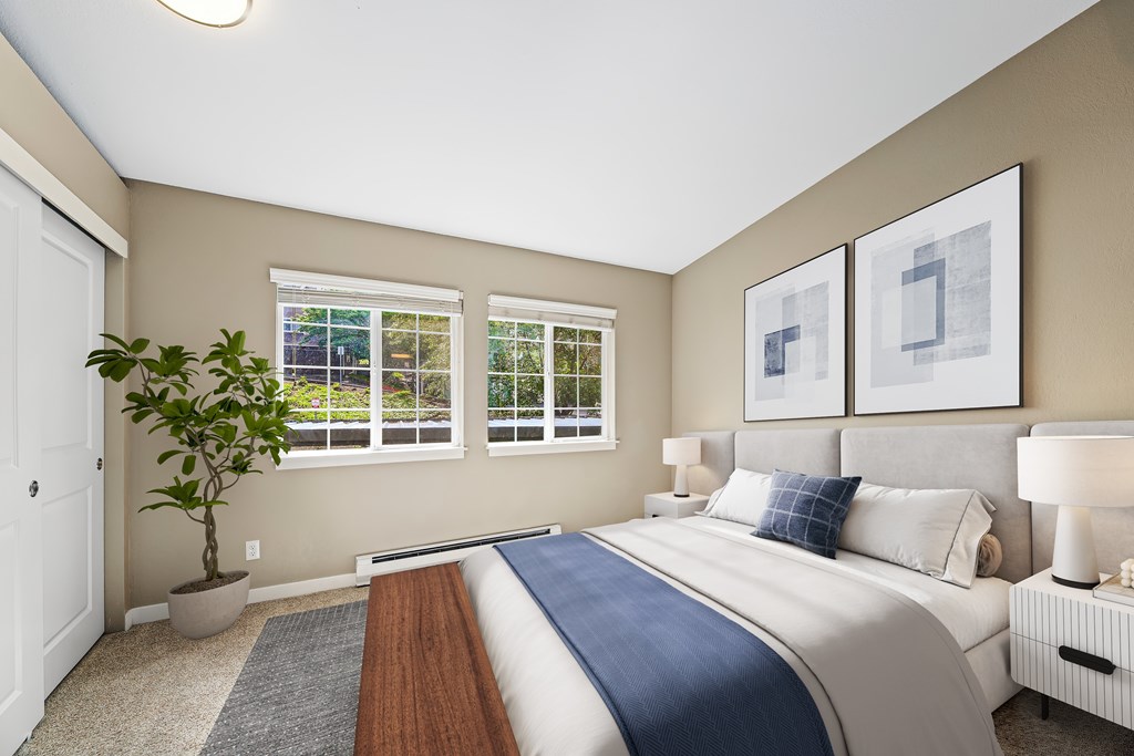 A bedroom with a large bed and a potted plant.