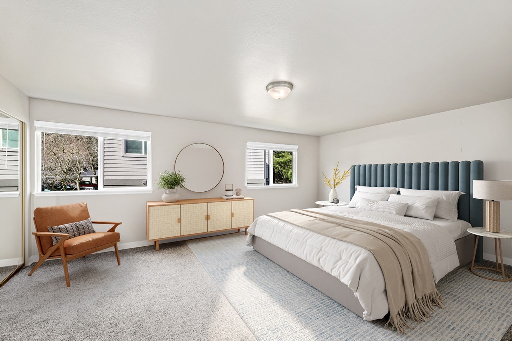 A bedroom with a bed, chair, and window.