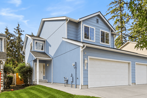 A blue house with white garage doors and a white door.
