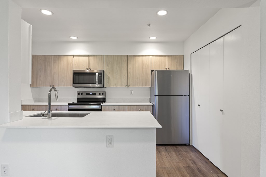 A modern kitchen with a stainless steel refrigerator and a white countertop.