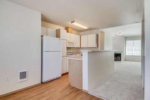 an empty kitchen with white cabinets and a white refrigerator
