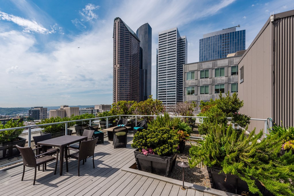 a roof deck with tables and chairs and a view of the city