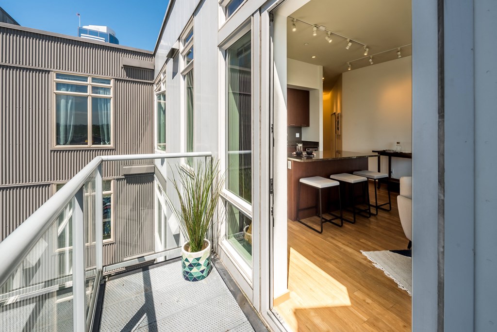a balcony with a table and chairs and a kitchen in the background