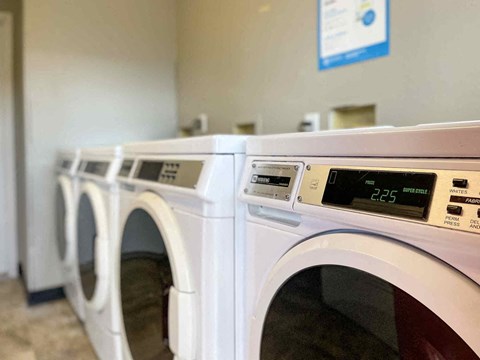 A row of washing machines with the front-loading machine displaying 2:25.