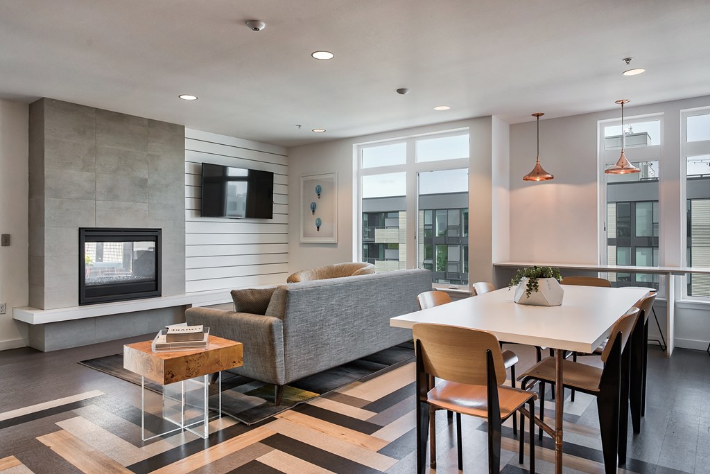A modern living room with a grey couch, a white coffee table, and a fireplace.