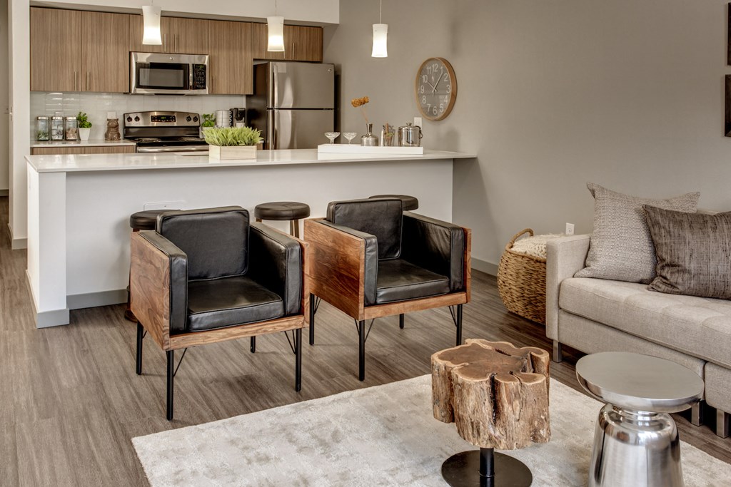 a living room with three chairs in front of a kitchen