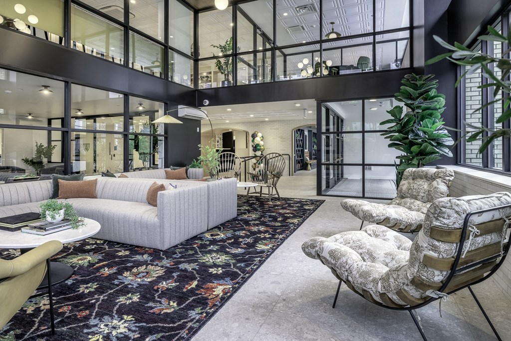 a living room with a white couch and chairs and a large floor to ceiling windows