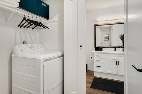 a small white laundry room with a washer and dryer and a white sink