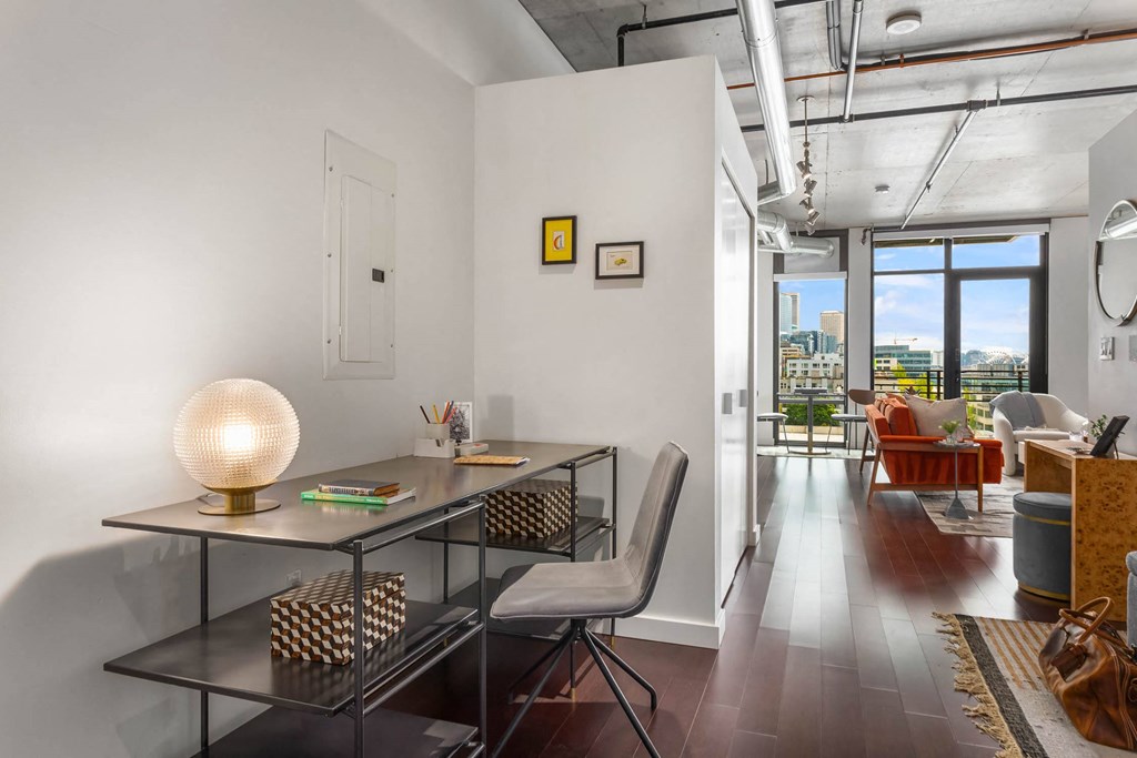 a home office with a glass desk and a view of a living room