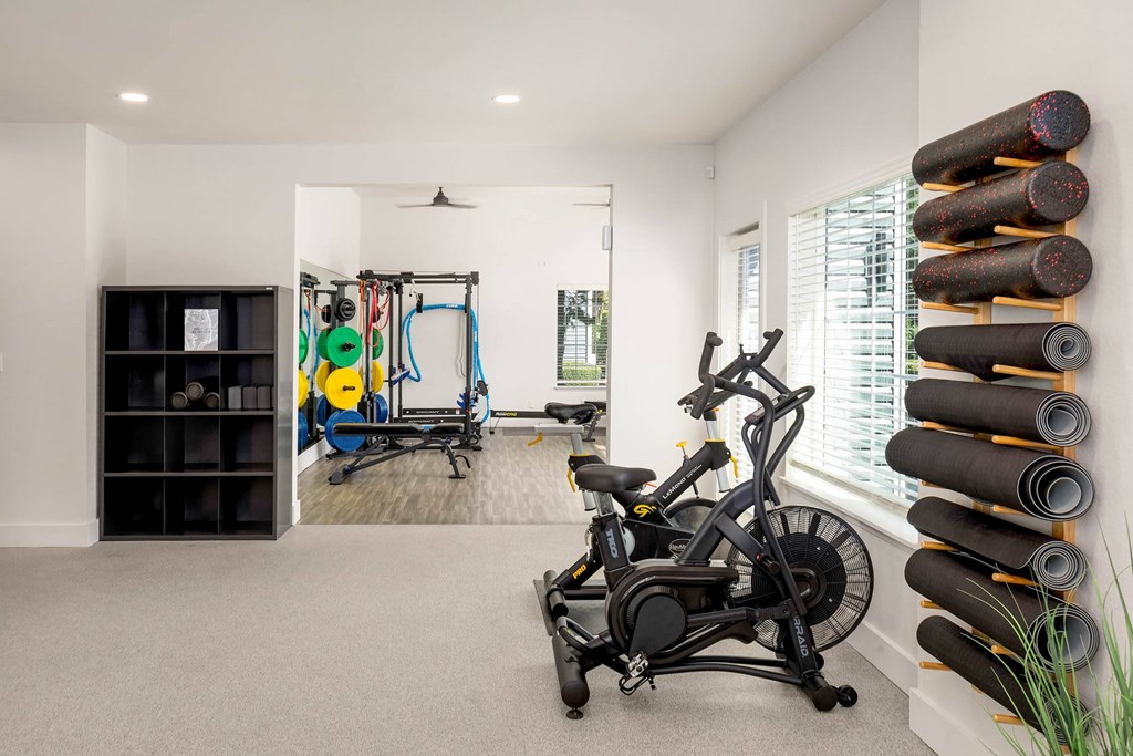 A room with a stationary bike and a wall of yoga mats.