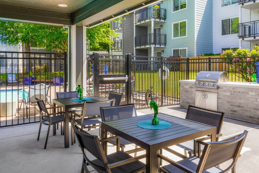 a patio with tables and chairs and a grill