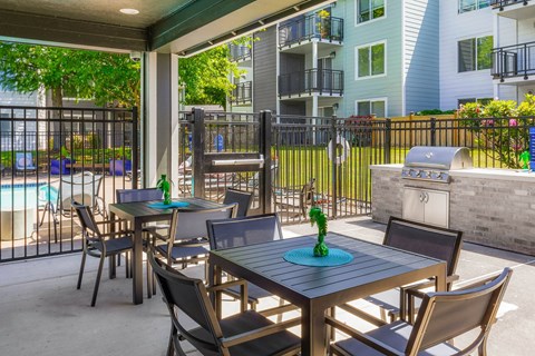 a patio with tables and chairs and a grill
