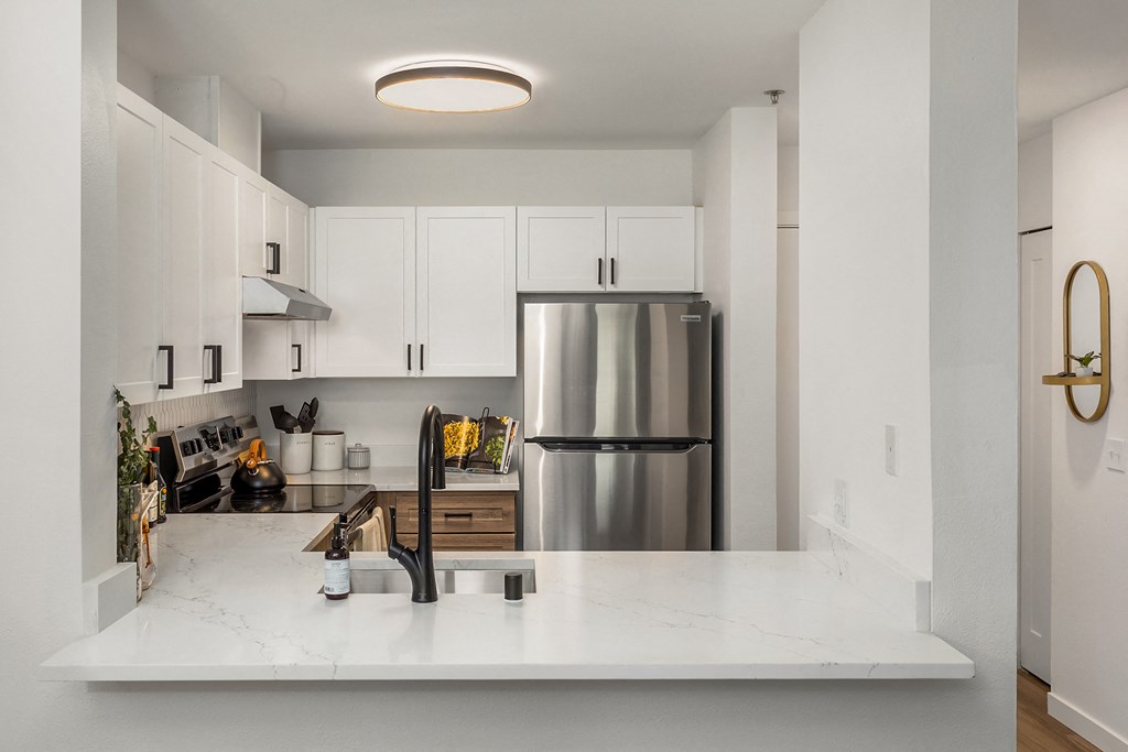 a kitchen with white counters and a stainless steel refrigerator