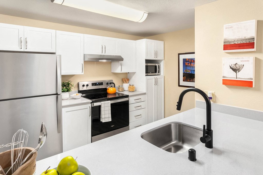a kitchen with white cabinets and a sink and a refrigerator