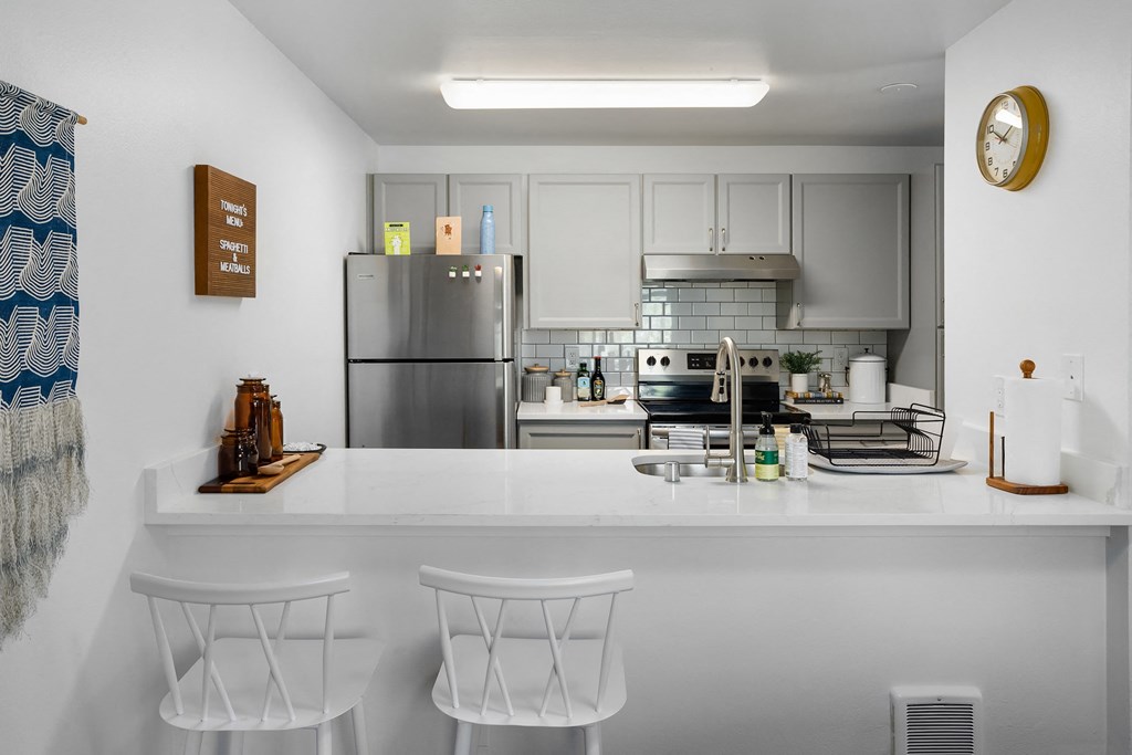 a kitchen with a white counter top and a stainless steel refrigerator