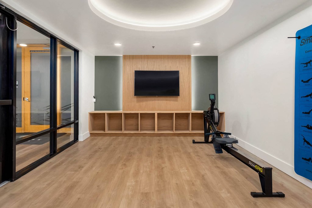 a home gym with a wall mounted tv and a treadmill