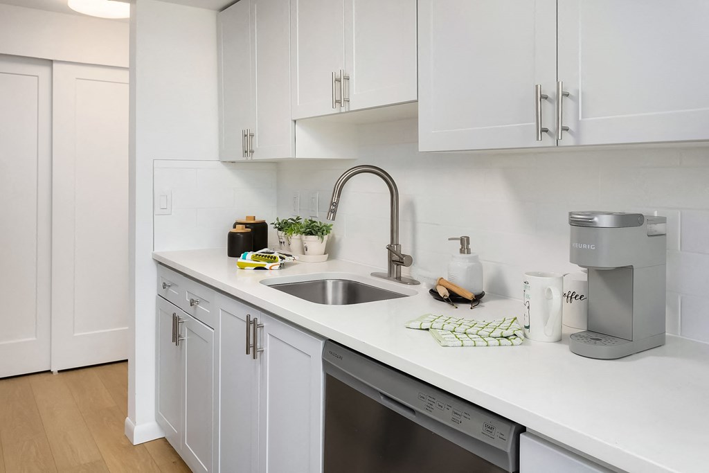 a renovated kitchen with white cabinets and a stainless steel sink