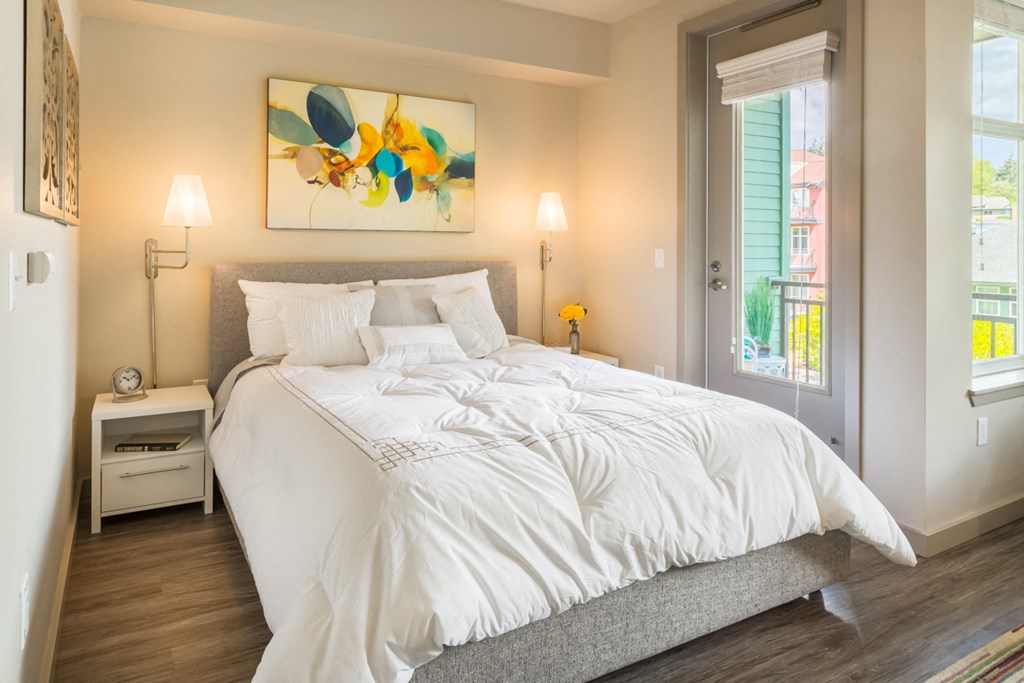 a bedroom with a large white bed and a painting on the wall