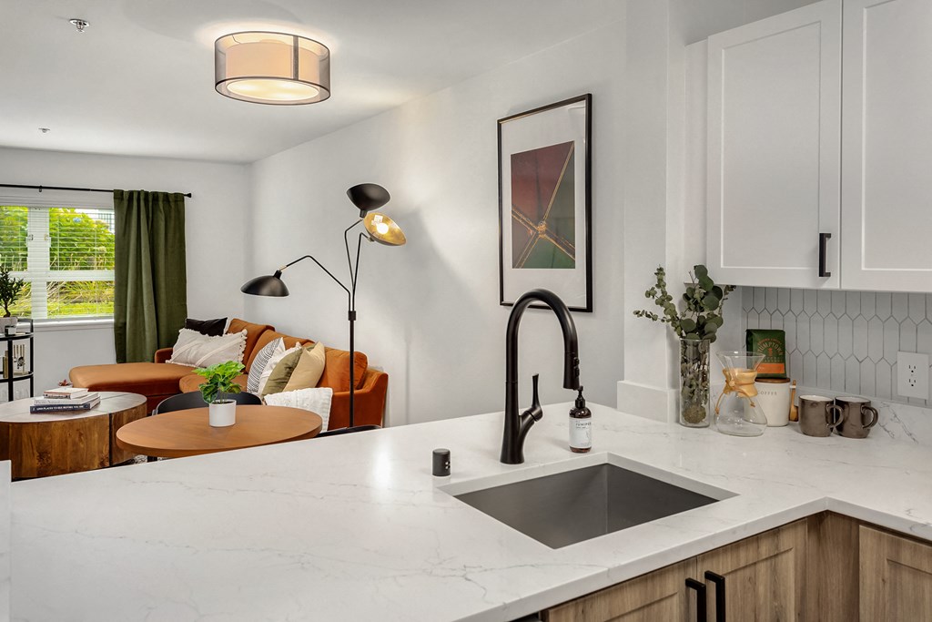 a kitchen counter with a sink and a living room with a couch