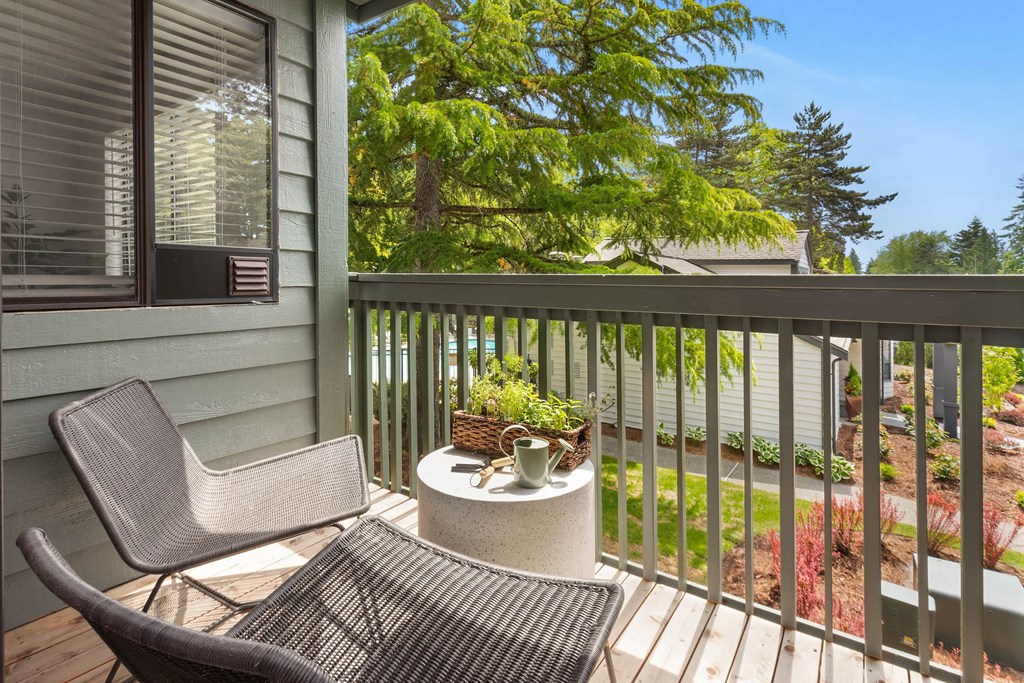 a balcony with two chairs and a table with a potted plant on it