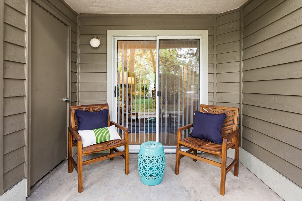 a covered porch with two chairs and a sliding glass door