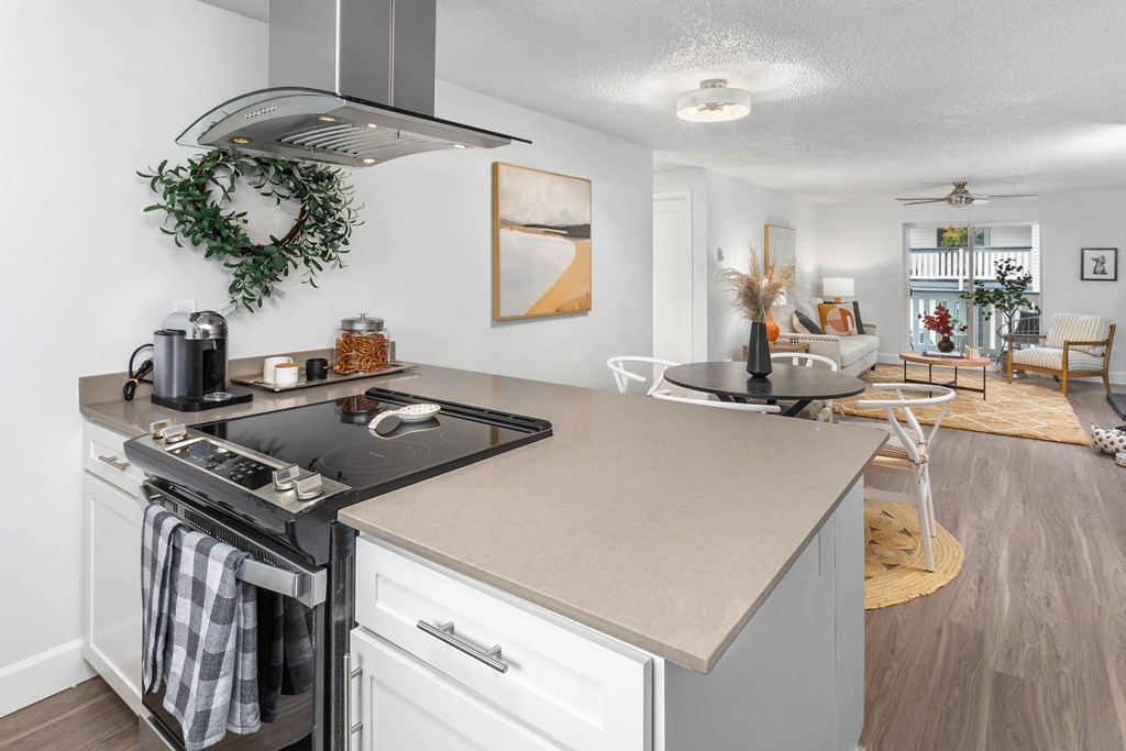 a kitchen with an island and a stove and a living room with a dining room
