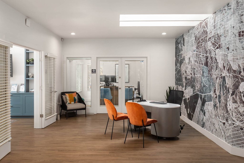 A room with a desk, chairs and a wall with a map on it.