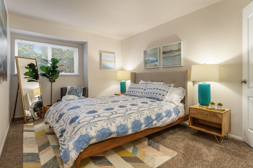 a bedroom with a bed and a mirror and a window