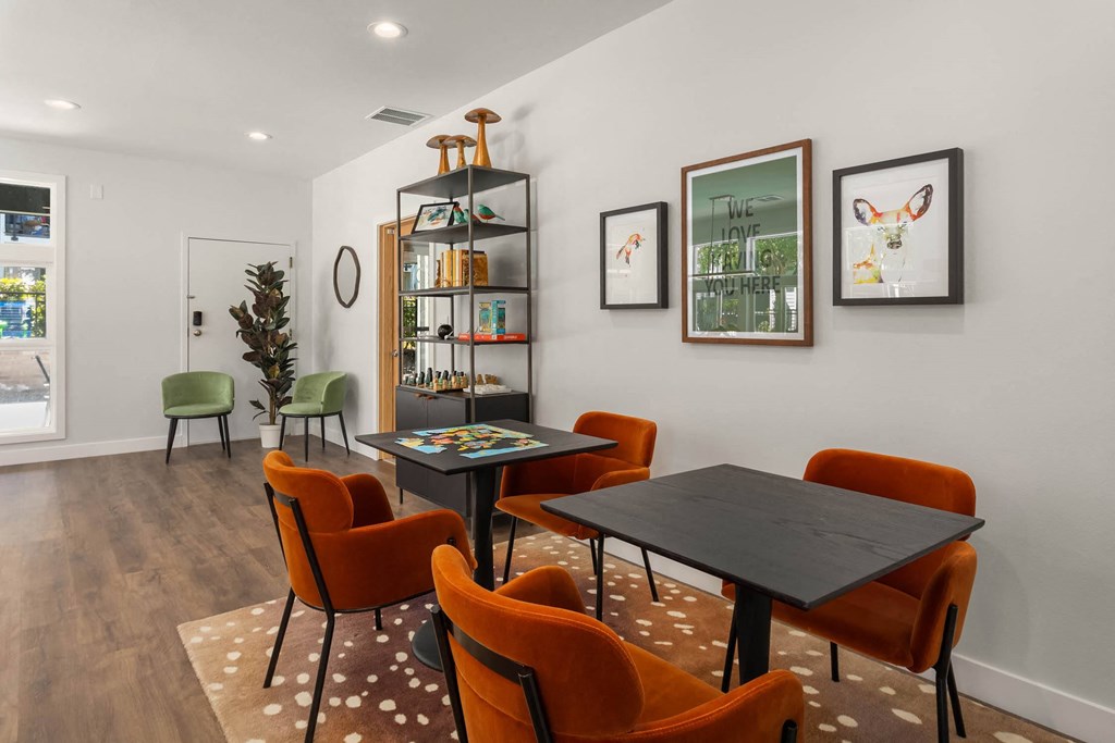 a room with a table with orange chairs and a bookshelf in the background