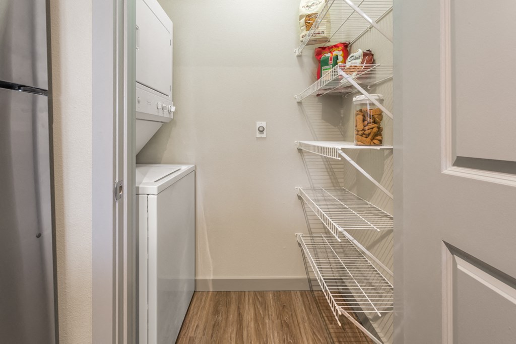 the spacious laundry room has a washer and dryer and a closet with shelves