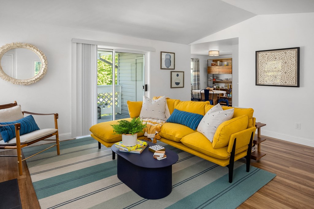 a living room with a yellow couch and a blue rug