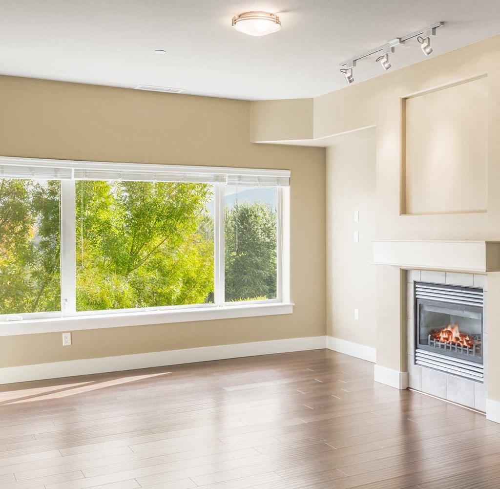 an empty living room with a fireplace and a large window