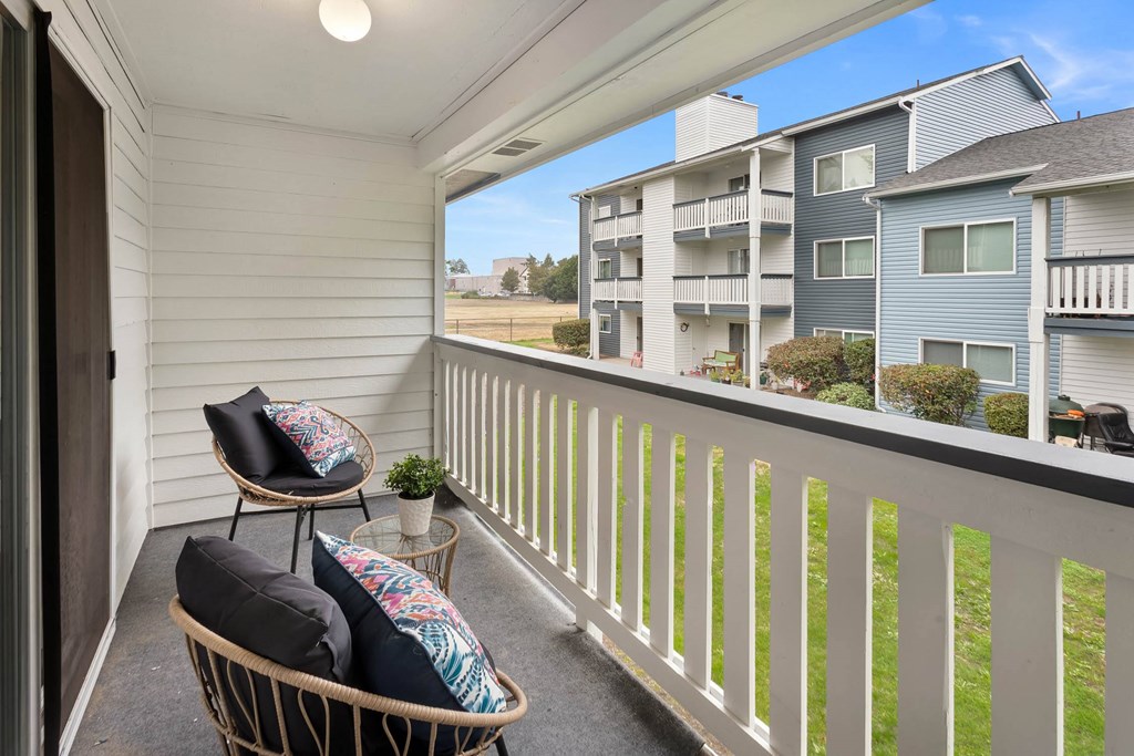A balcony with a chair and a table with a potted plant on it.