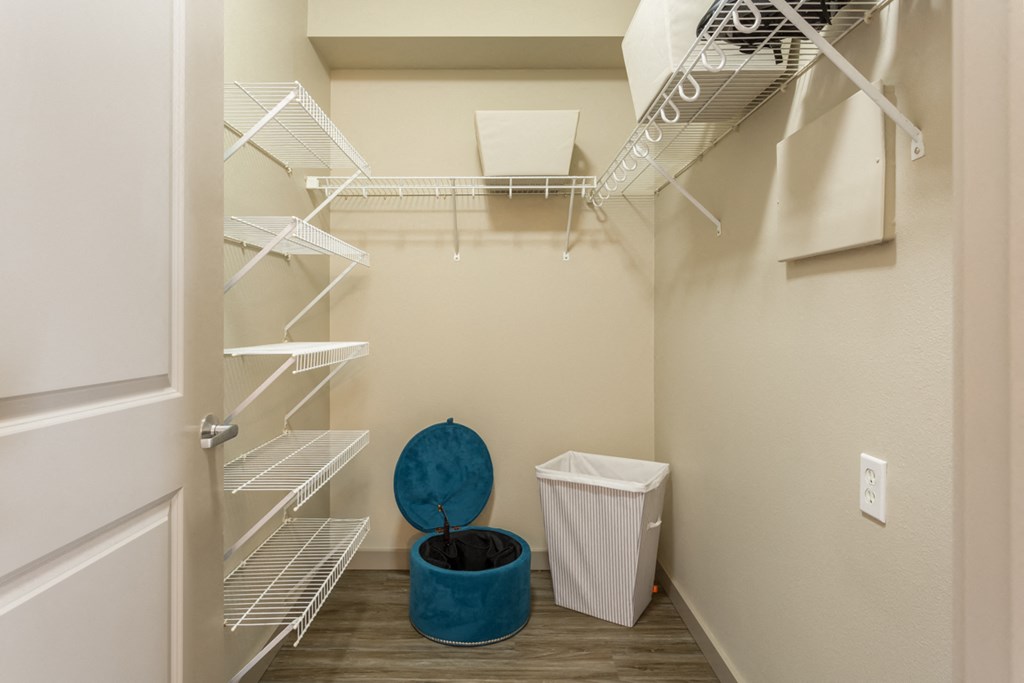 a walk in closet with a basket and a trash can in a room with a