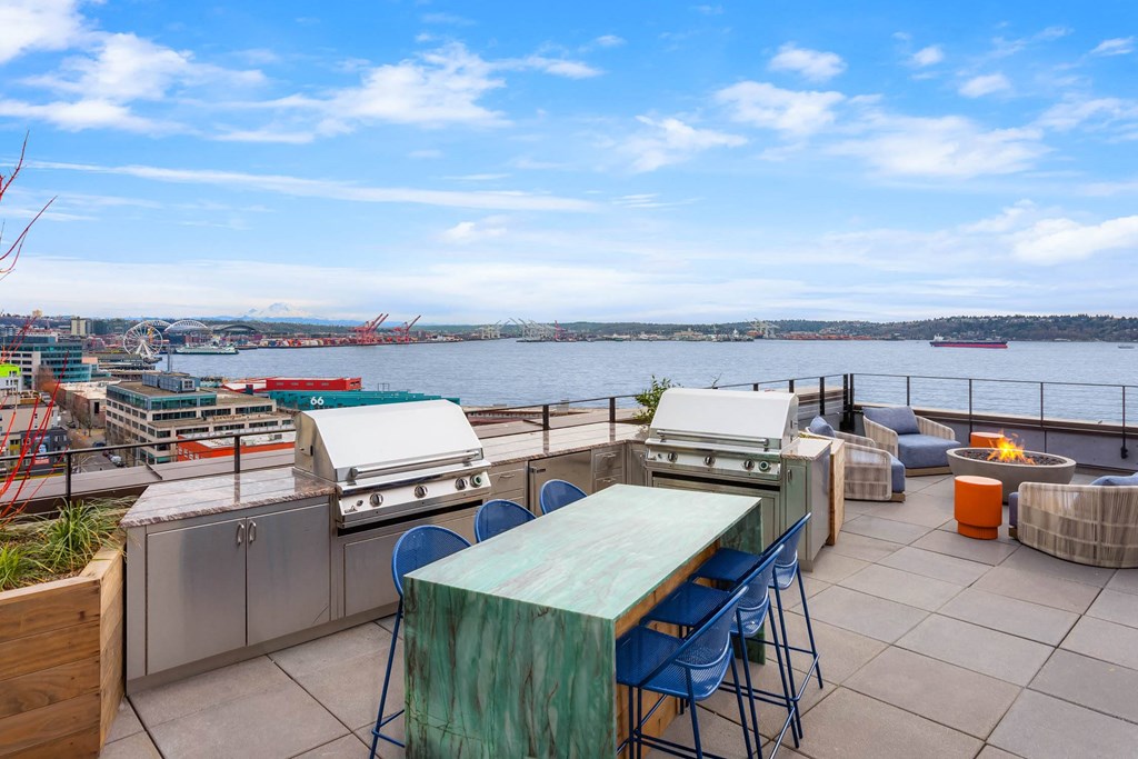 the rooftop patio has a table and barbecue grill and a view of the water