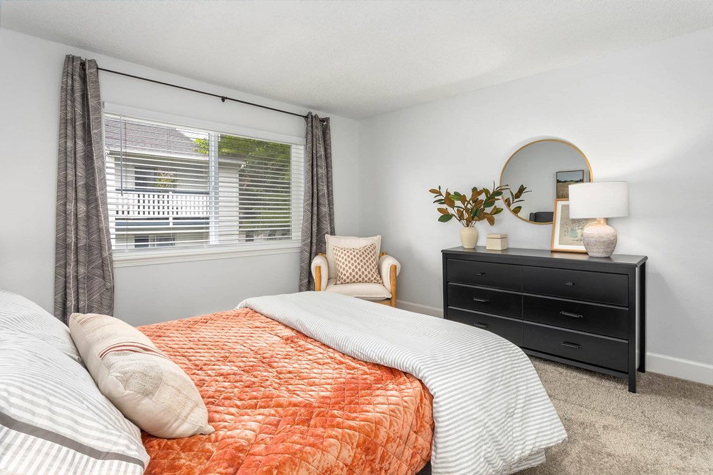 A bedroom with a bed, nightstand, and chair.