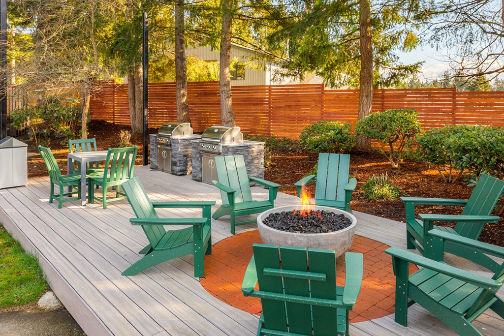 a patio with adirondack chairs and a fire pit