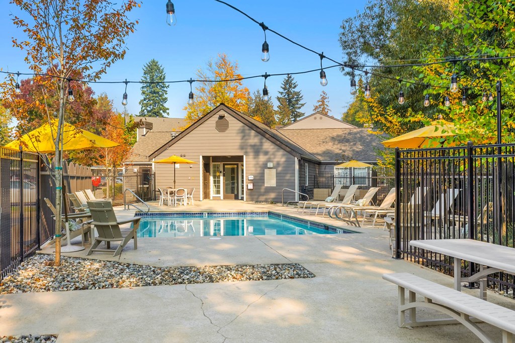 the pool is next to a house with chairs and umbrellas