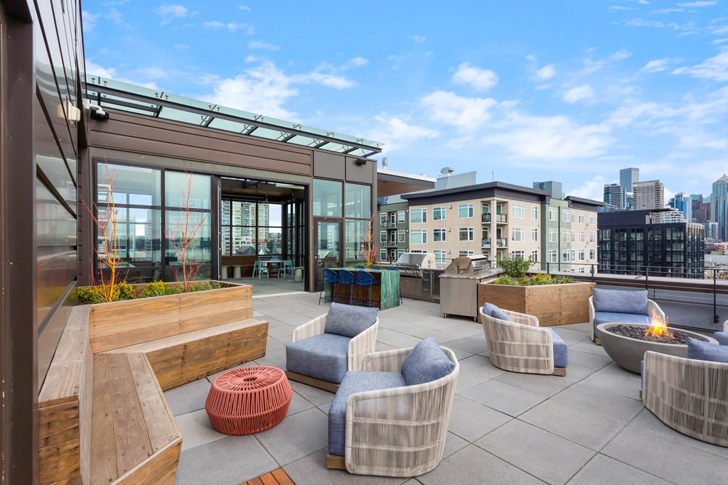a rooftop patio with couches and chairs and a fire pit