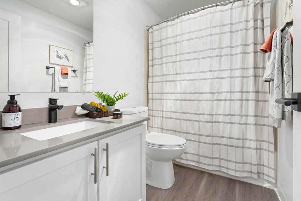 A white bathroom with a toilet, sink, and shower curtain.