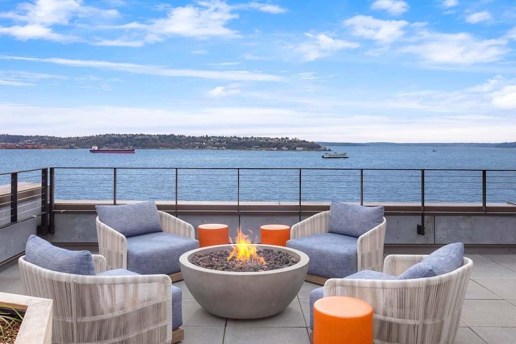 a patio with chairs and a fire pit overlooking the water