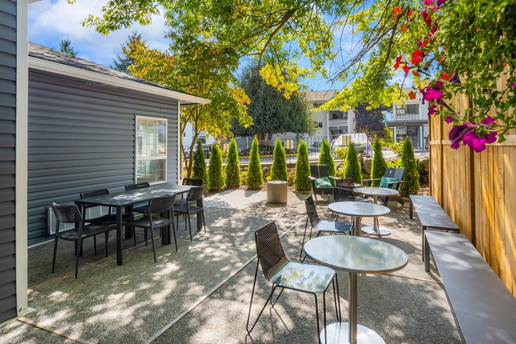 A patio with a table and chairs is surrounded by trees.