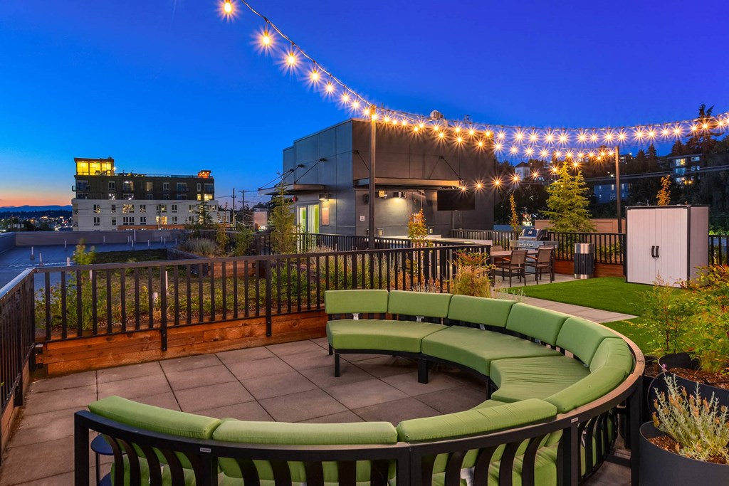 a rooftop patio with green furniture and lights