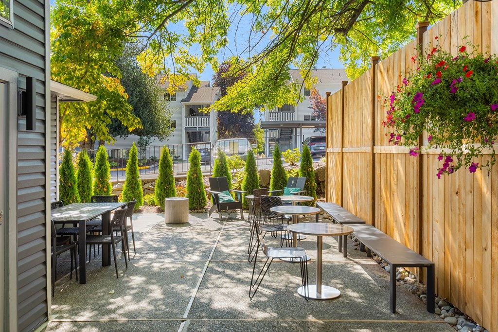 A patio with tables and chairs surrounded by a wooden fence.