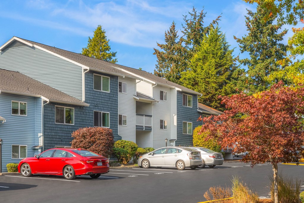 an apartment building with cars parked in a parking lot
