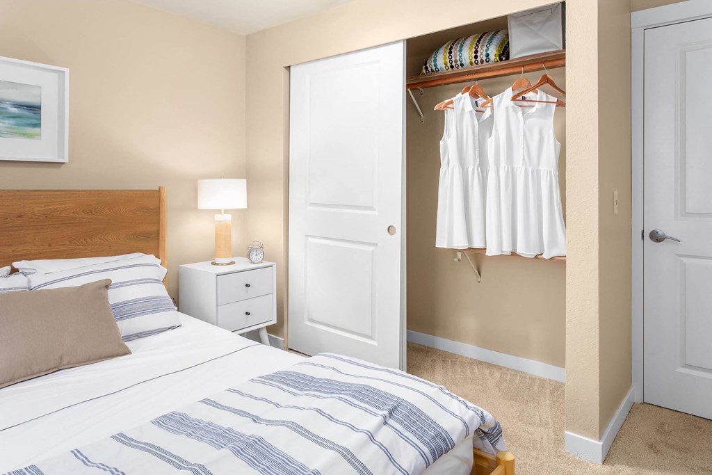 a bedroom with a bed and closet with a closet door and a closet with clothes