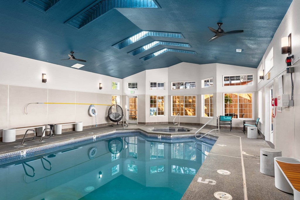 A large indoor swimming pool with a wooden bench and a fan.