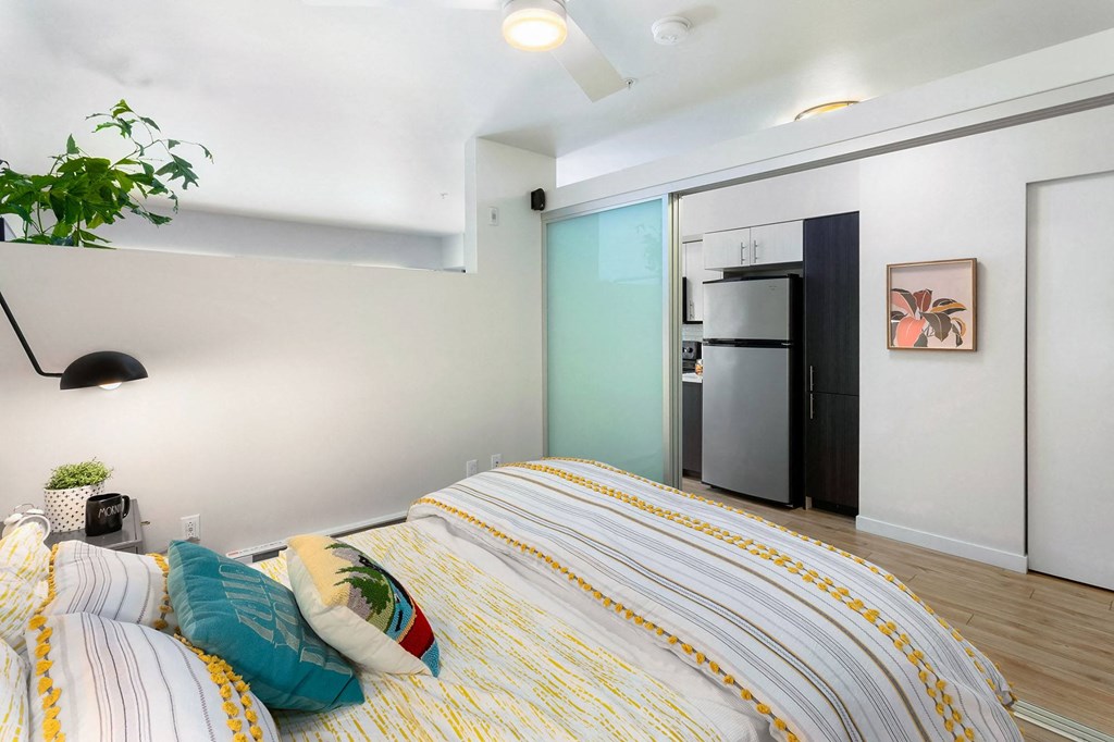 a bedroom with a bed and a refrigerator