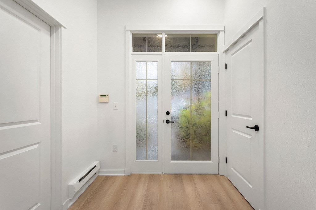 the entrance to a home with white walls and a glass door