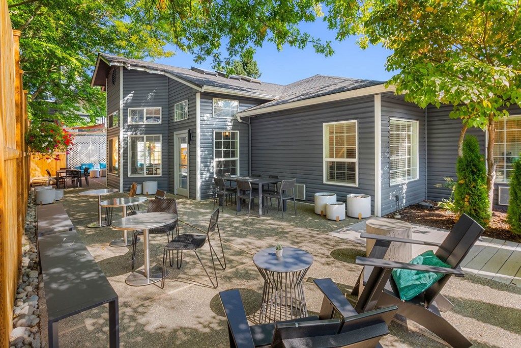 A grey house with a patio and chairs.